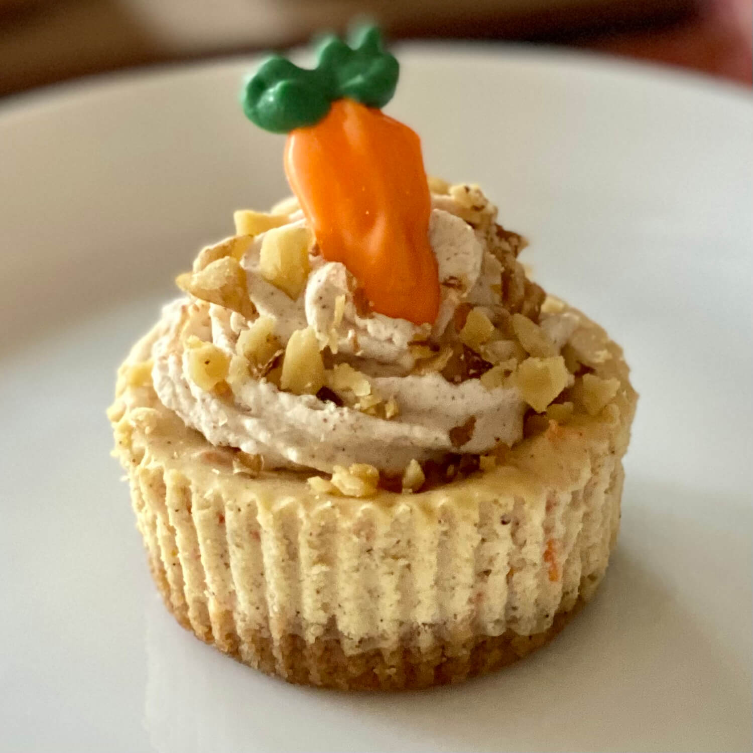 Carrot Cake Carrot Cake - Is filled with all of the warm delicious flavors that you would expect to find in a carrot cake. The graham cracker crust is enhanced with the flavors of brown sugar and walnuts. The cheesecake is smooth and creamy with warm spices to add flavor. It is topped with cinnamon cream cheese whipped cream and finished off with toasted walnuts and a candy carrot for decoration.